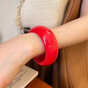 Close-up of minimalist red resin bangle on wrist with a vintage retro aesthetic