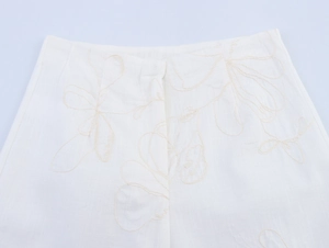 Nahaufnahme der beige Blumenstickerei auf dem weißen Baumwolle-Leinen-Hosenstoff