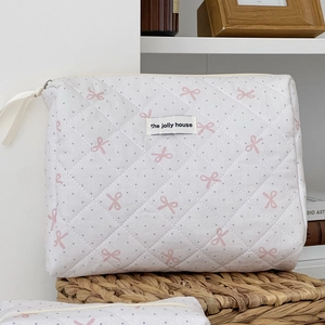 Detailed close-up of quilted cotton makeup bag with pink bows and polka dots
