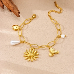 Détail du bracelet en acier doré avec breloques perle, marguerite et pendentif coeur