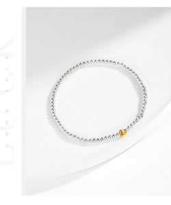 Minimalist silver beaded bracelet featuring a single matte gold bead as a focal point