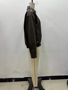 Detail of dark brown faux leather bomber jacket showing collar and ribbed hem texture