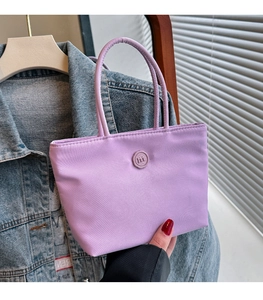 Détail du sac seau en nylon violet avec logo M gaufré et doubles poignées robustes