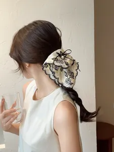 Detail of vintage beige floral scrunchie with lace trim, pearl, and black bow accessory
