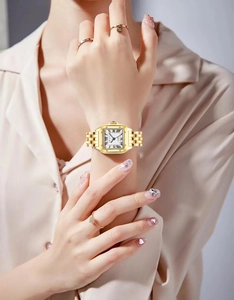 Détail de la montre à quartz carrée dorée pour femme avec chiffres romains portée au poignet