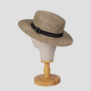 Detail of hand-woven natural straw hat with a flat top and black ribbon decoration