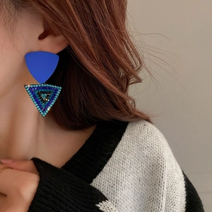 Detailed close-up of blue geometric triangle earrings with vibrant crystal inlay