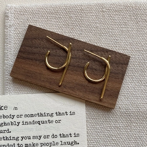 Detail of minimalist gold geometric S925 sterling silver earrings on a wooden base