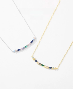 Macro shot of silver and gold necklaces with curved colorful marquise zircon pendants