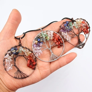 Handheld view of heart and round life tree wire wrapped crystal pendants with black wax cord