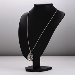 Silver curb chain necklace with an oval embossed portrait pendant on a black mannequin