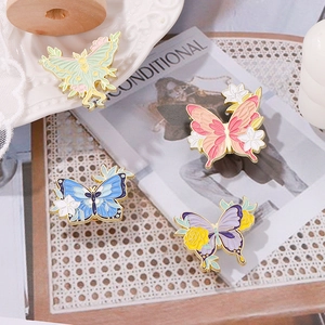 Juego de cuatro coloridos broches de mariposa en esmalte con detalles florales y bordes de oro