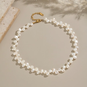 Elegant natural baroque freshwater pearl necklace with gold clasp on minimalist stone background