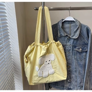 Detail of yellow canvas tote bag featuring a cute white plush puppy dog patch applique