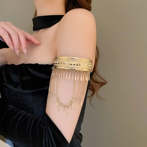 Détail d'un brassard en métal doré avec glands bohèmes et pendentifs feuilles délicats