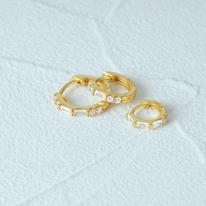 Detail of three gold S925 silver hoop earrings with rectangular and round cubic zirconia