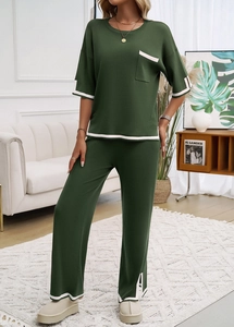 Détail de l'ensemble en tricot vert avec liseré blanc et pantalon fendu dans un salon moderne