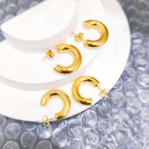Minimalist thick C-shaped hoop earrings in 18k gold finish with polished metal texture