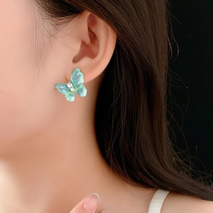 Détail d'une boucle d'oreille papillon vintage verte avec diamants sur un mannequin