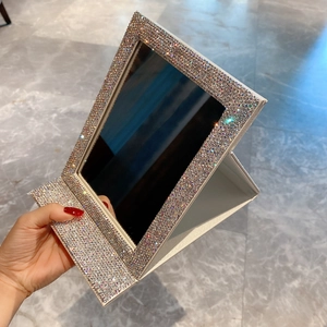 Detail of silver foldable makeup mirror with sparkling rhinestones and white base