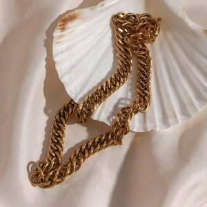 Close-up of gold chunky curb chain necklace with toggle clasp on shell and silk