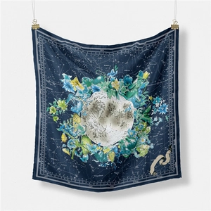 Artistic square silk scarf with moon and botanical prints hanging on a white wall