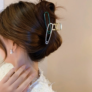 Detail of safety pin hair claw clip in green and white on a model's hair