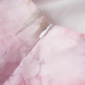 Detail van onzichtbare rits op roze en witte tie-dye organza jurk met zachte textuur