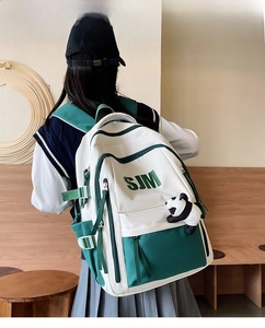 Detail of white and green college backpack featuring SJM logo and panda charm accessory
