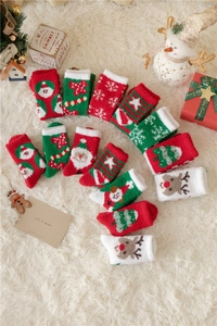 Vue à plat de chaussettes de Noël festives en polaire corail avec motifs cerf et sapin