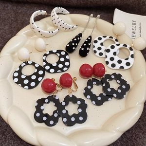Detailset von gepunkteten Blumenohrringen und Vintage-Reifen in einer Keramikschale