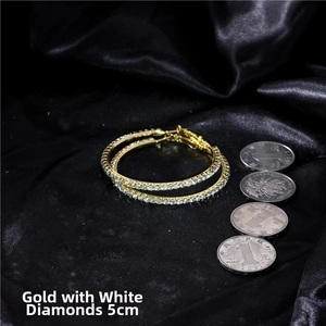 Detail of 5cm gold hoop earrings with white crystals on black silk background