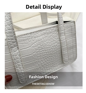 Detail of white crocodile embossed leather bag showing precise stitching and texture