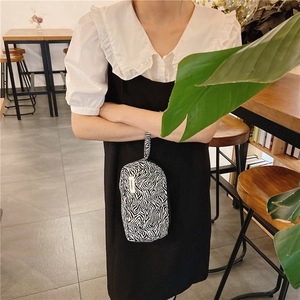 Trousse à maquillage élégante en toile zébrée tenue en main pour la taille au café
