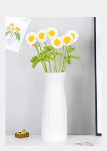 Detail of hand-crocheted white daisy bouquet in a textured white ceramic vase