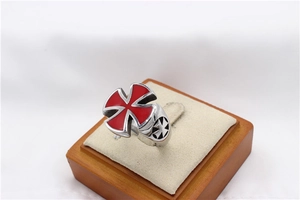 Macro shot of punk style steel ring with red enamel Maltese cross on wooden display