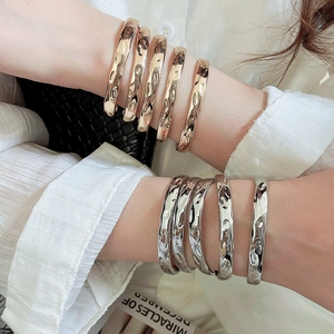Detailed view of hammered texture on stacked minimalist gold and silver metal bangles