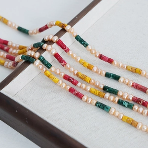 Handmade freshwater pearl necklace with colorful natural stone beads on a wooden tray