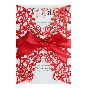 Detail of red glitter laser-cut wedding invitation with elegant satin bow and floral card