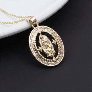 Detailed macro shot of a golden Virgin Mary pendant with sparkling zircon inlays on a white plate