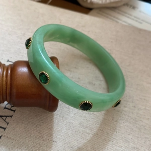 Detailed close-up of retro green acrylic bangle with gold-edged emerald rhinestones