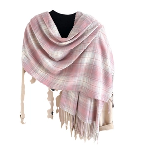 Pink and white plaid cashmere-like scarf with fringe on a beige coat over black sweater