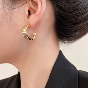 Detail showing gold C-shaped lava textured earrings worn on a model for a vintage look