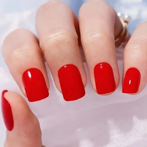 Glossy classic red short square press-on nails displayed on a white lace background