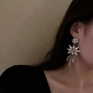 Macro view of crystal flower drop earrings with silver tassels on female model