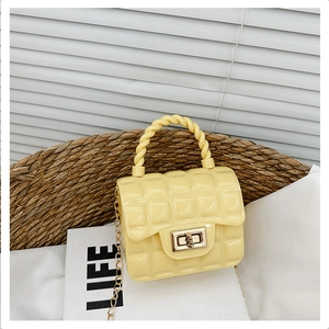 Macro detail of yellow quilted jelly bag with gold twist lock and chain on woven basket