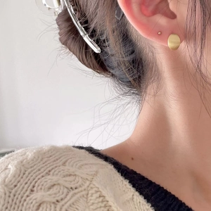 Close-up of minimalist brushed gold circular stud earring on model with soft lighting