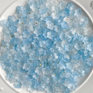 Macro view of blue and white gradient resin flower beads with sparkling gold glitter detail