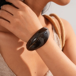 Detail view of a wide acrylic coffee brown bangle with smooth polished resin finish