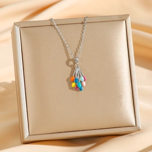 Silver necklace featuring a colorful balloon pendant against elegant golden satin background